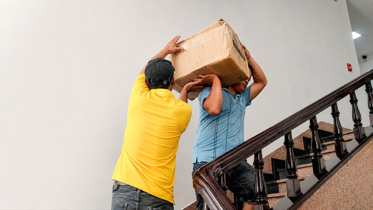 Nhân viên bê thùng đồ qua cầu thang khi chuyển nhà trọn gói Thanh Xuân